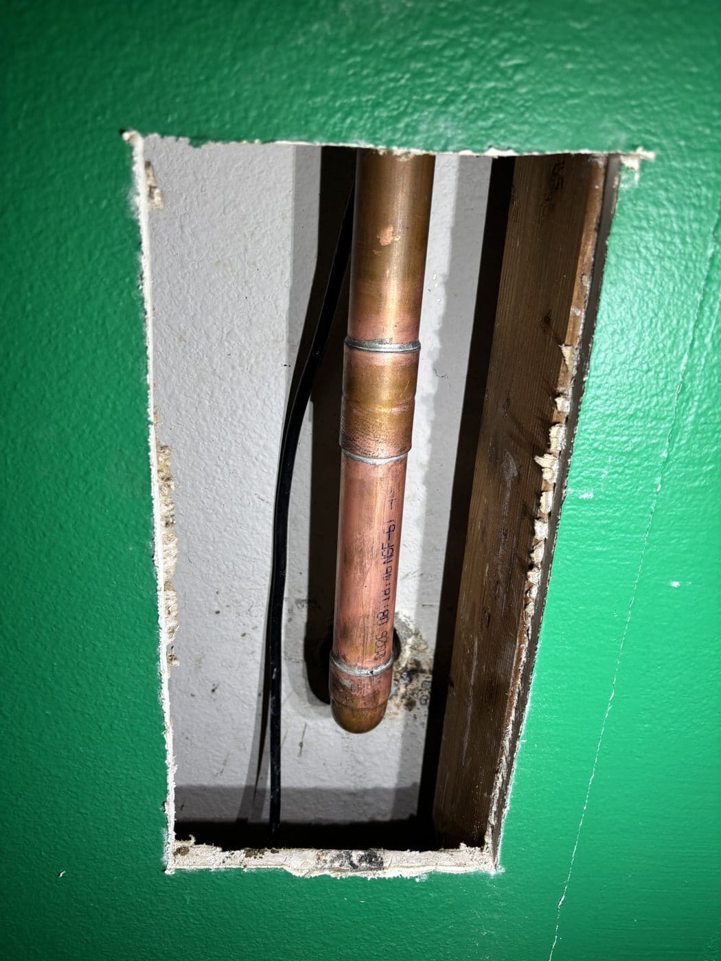Copper pipe exposed through a wall access opening